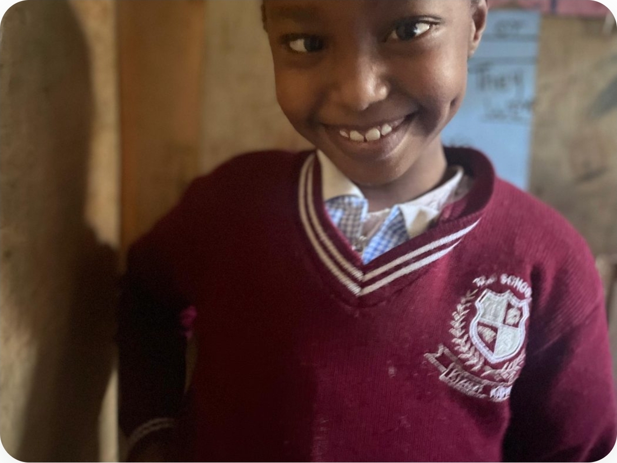 A student in a maroon school jumper smiling in class