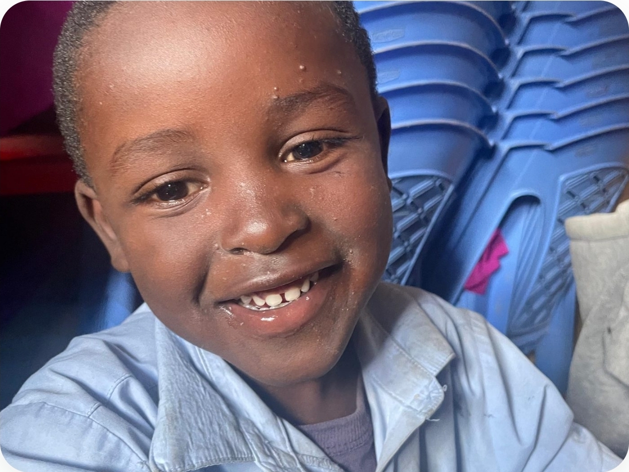 A boy in a light blue school shirt laughing at the center