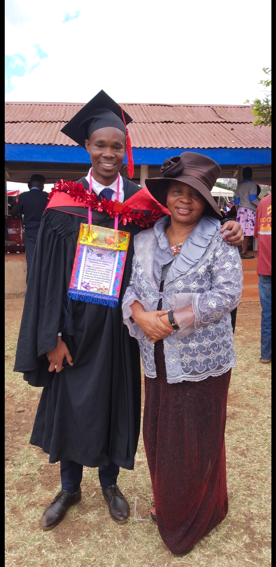A Charisma Tumaini scholar in cap and gown with founder Dr. Grace Manjau at his university graduation